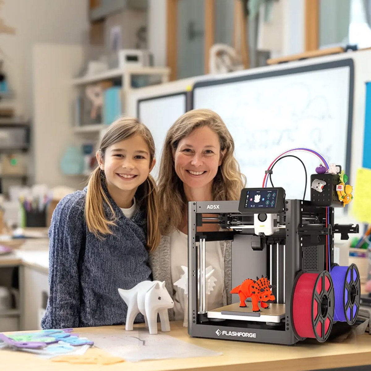 Een vrouw en een meisje naast een FlashForge Adventurer 5X met kleurrijke 3D-geprinte dieren