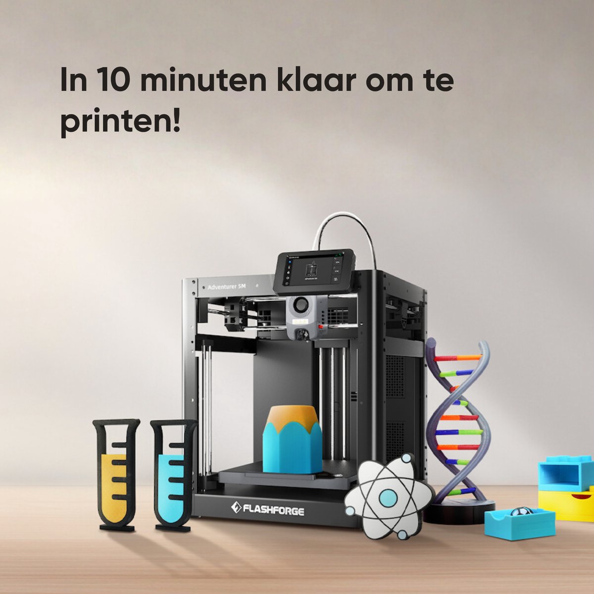 FlashForge Adventurer 5M naast 3D-geprinte reageerbuizen, een DNA-model en kleurrijke prints